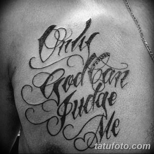 Черно-белое фото татуировки с надписью 'Only God can judge me' на плече мужчины. Изящный шрифт, плавные линии, элегантный дизайн.