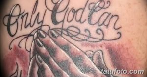 Фото тату надписи 'Only God Can Judge Me' с изображением молящихся рук. Детализированный рисунок татуировки в черно-серых тонах.