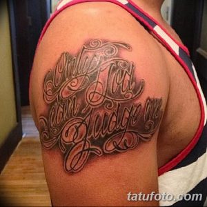 Фото тату надписи 'Only God Can Judge Me' в стиле олдскул, выполненной на плече. Детализированный рисунок татуировки с использованием черных и серых оттенков.