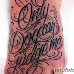 Фото тату надписи 'Only God Can Judge Me' на стопе. Черно-серая татуировка, выполненная каллиграфическим шрифтом с узорами.