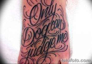 Фото тату надписи 'Only God Can Judge Me' на стопе. Черно-серая татуировка, выполненная каллиграфическим шрифтом с узорами.