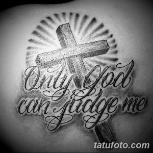 Фото тату креста с надписью 'Only God can judge me' на плече. Черно-белое изображение, реалистичный стиль, лучи света.