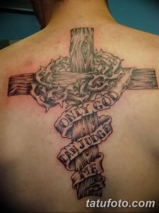 Фото тату креста с надписью 'Only God Can Judge Me' на спине мужчины. Черно-серые тона, детализированное изображение.