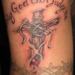 Фото тату креста с надписью 'Only God can judge me' на руке. Изображение выполнено в реалистичном стиле с использованием черных и красных оттенков.