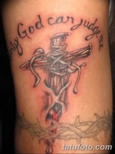 Фото тату креста с надписью 'Only God can judge me' на руке. Изображение выполнено в реалистичном стиле с использованием черных и красных оттенков.
