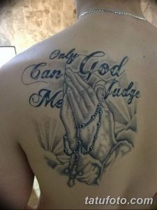 Фото тату на спине: молящиеся руки с четками и надписью 'Only God Can Judge Me', выполненное в реалистичном стиле с использованием серых оттенков.