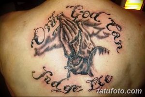 Фото тату на спине: молящиеся руки с крестом и надписью 'Only God Can Judge Me', выполненное в черно-серых тонах с использованием мягких теней.