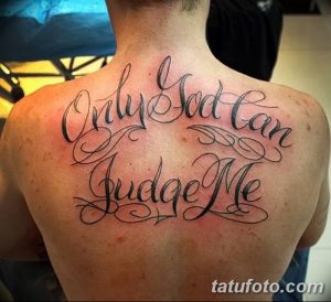 Фото тату надписи 'Only God Can Judge Me' на спине мужчины. Надпись выполнена в изящном шрифте с завитушками, черным цветом.