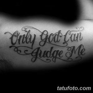 Фото тату надписи 'Only God Can Judge Me' на руке, выполненной в классическом стиле. Текст выполнен черным цветом, с четкими линиями.