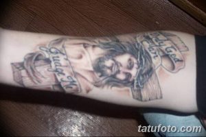 Фото тату на руке, изображающее Иисуса Христа с крестом и надписью 'Only God Can Judge Me'. Татуировка выполнена в черно-серых тонах, с высокой детализацией.