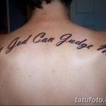 Фото тату надписи 'Only God Can Judge Me' на спине мужчины. Надпись выполнена в изящном шрифте с плавными линиями, черным цветом.
