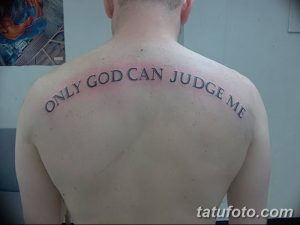 Фото тату надписи 'Only God Can Judge Me' черным цветом на спине мужчины. Текст изогнут по форме плеч, выполнен в классическом шрифте.