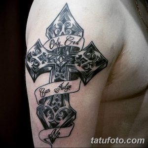 Фото татуировки на плече с изображением креста и надписью 'Only God Can Judge Me'. Детализированный рисунок в готическом стиле.