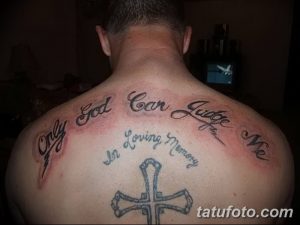 Фото тату на спине с крестом, надписью 'Only God Can Judge Me' и текстом 'In Loving Memory'. Черно-серый рисунок татуировки.