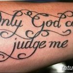 Фото тату надписи 'Only God can judge me' на мужском запястье. Черно-серый рисунок татуировки выполнен элегантным шрифтом с декоративными элементами.