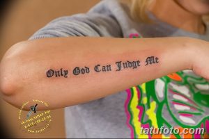 Фото тату надписи 'Only God Can Judge Me' на предплечье девушки. Черный шрифт в готическом стиле.
