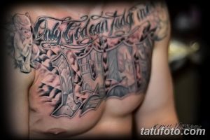 Фото большой татуировки на груди и плече с надписью 'Only God Can Judge Me', изображением ангела и большой буквой 'A'. Сложный дизайн в серо-черных тонах.