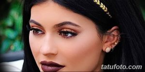Фото тату с золотыми узорами на ухе и виске девушки. Изящные линии и геометрические формы.