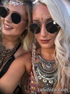 Фото двух девушек с длинными волосами, украшенными блестками и массивными серебряными ожерельями, демонстрирующими временные татуировки в богемном стиле.