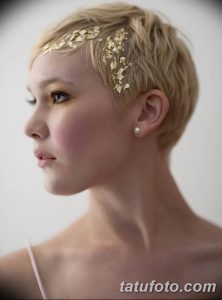 Фото тату: девушка с короткой стрижкой, украшенная золотыми тату в виде листьев на висках. Элегантный и утонченный образ.