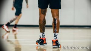 Фотография ноги баскетболиста с татуировкой "Supreme". Татуировка нанесена вдоль голени и хорошо видна на крупном плане.