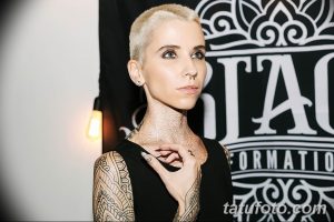 Фотография девушки с короткими светлыми волосами и множеством черных татуировок на шее, плече и руке.