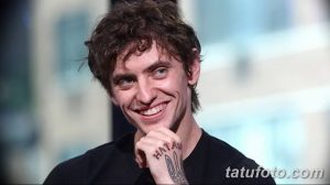 Фотография мужчины с татуировкой на руке, изображающей надпись "HATAW" и символический рисунок. Мужчина улыбается в камеру.