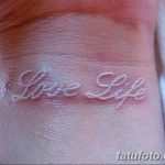 Фото белой татуировки на запястье: надпись "Love Life", выполненная каллиграфическим шрифтом, выглядит изящно и вдохновляюще.