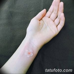 Фото белой татуировки на запястье: нежный цветок с четырьмя лепестками, выполненный в технике white ink, выглядит изящно.