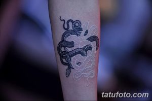 Фото тату на предплечье с изображением двух змей, символизирующих Инь и Ян, выполненное в черном и белом цвете.