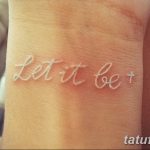 Фотография татуировки с надписью 'Let it be' выполненной тонким белым шрифтом на пальце руки.