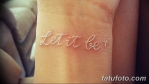 Фотография татуировки с надписью 'Let it be' выполненной тонким белым шрифтом на пальце руки.