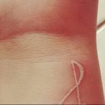 Фото белой татуировки на запястье в виде абстрактного рисунка. Минималистичный эскиз татуировки, выполненный белыми чернилами.