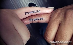 Фото татуировки на пальцах: слово "Promise" написано на обоих пальцах, создавая эффект зеркального отражения.