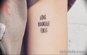 Фото тату с надписью "Love Yourself First". Небольшая, черная татуировка на запястье. Минималистичный стиль, мотивационная надпись.
