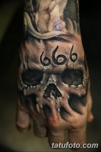 Фото тату на тыльной стороне руки с изображением черепа и числа 666. Реалистичная татуировка в темных тонах.