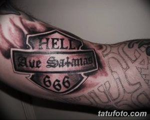 Фото татуировки с надписью 'Hell Ave Satana' и числом 666 на предплечье. Черно-белый рисунок татуировки в готическом стиле с мрачной тематикой.