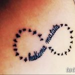 Фото тату: черная татуировка с надписью 'Hakuna Matata' в форме символа бесконечности, украшенного птицами. Яркий и позитивный дизайн.