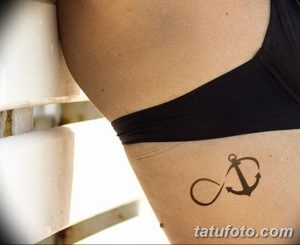 Фото тату с изображением якоря, объединенного с символом бесконечности на боку. Тонкие линии, лаконичный дизайн. Символизирует надежду и вечную любовь.