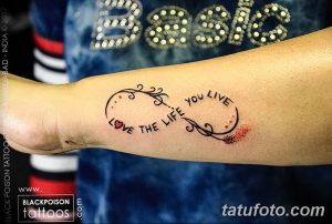 Фото тату: надпись "Love the life you live" в виде спирали на запястье, украшенная небольшими сердечками и капельками крови. Красивый и мотивирующий рисунок татуировки.