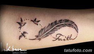 Фото тату на предплечье: черное перо с летящими птицами и надписью 'Faith'. Изящный рисунок татуировки, выполненный в графичном стиле.