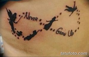 Фото татуировки на коже: силуэты Питера Пэна и Венди, надпись 'Never Grow Up' и звезды. Черно-белый рисунок, сказочный стиль.
