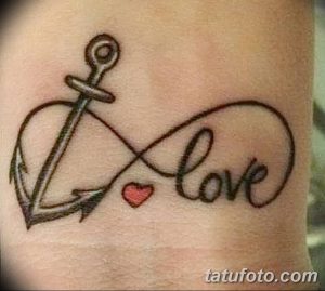 Фото тату с изображением якоря, переплетенного со словом 'Love' и маленьким сердцем. Черно-белая татуировка, нежный дизайн, символ любви и надежды.