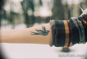 Фото тату ласточки на запястье. Черно-белый рисунок, детализированный стиль, женственный дизайн.