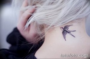 Фото тату маленькой ласточки на шее. Черно-белый рисунок татуировки, выполненный в минималистичном стиле, с акцентом на линии.
