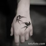Фото тату двух ласточек на руке. Черно-белый рисунок татуировки, выполненный в графическом стиле, с четкими линиями и детальной проработкой.