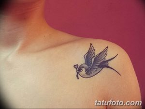 Фото тату ласточки с ключом на плече. Нежный и минималистичный рисунок татуировки в синих тонах.