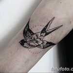 Фото тату ласточки с цветами на руке, выполненной в технике blackwork с точками. Детализированный рисунок татуировки.