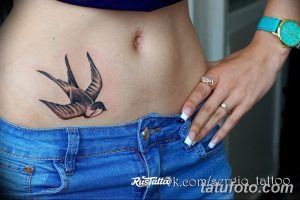 Фото тату ласточки в стиле олдскул на бедре девушки. Яркий рисунок татуировки с использованием насыщенных цветов и четких контуров, характерных для традиционного стиля.
