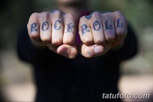 Фото тату надписи 'ROCKROLL' на костяшках пальцев. Черный рисунок татуировки выполнен четкими линиями, демонстрируя смелый и бунтарский стиль.